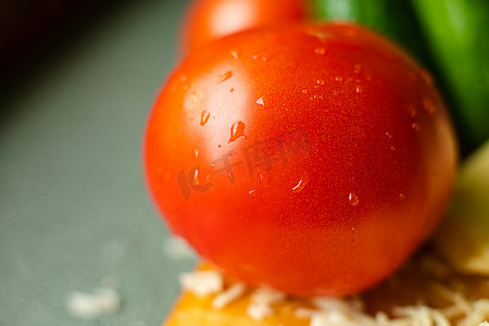 桌子上放着一个洗过的纯红番茄，上面有水滴