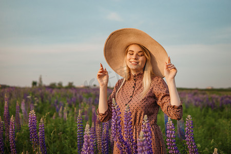 漫步摄影照片_一位戴着草帽的美丽女子走在开满紫色花朵的田野里。