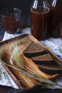 木盘上的黑麦面包和黑麦小穗片，配有瓶子和一杯克瓦斯 — 黑麦面包发酵的产品，传统的俄罗斯饮料。