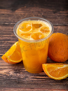 榨摄影照片_木桌上有冰块的鲜榨橙汁