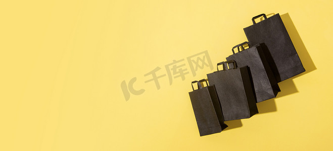 黑色星期五销售黄色背景的黑色购物袋，带有横幅格式的复制空间