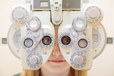 一名男性眼科医生使用综合屈光检查仪检查女孩的视力。