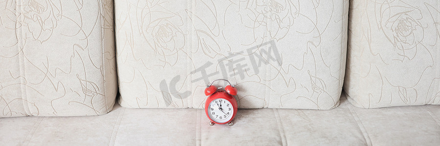 米色沙发和上面的红色复古时钟显示已近午夜