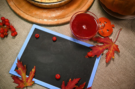 红酒蛋糕摄影照片_空白黑板的顶部视图，带有广告文字、枫叶秋叶和桌上一杯热红酒的复制空间