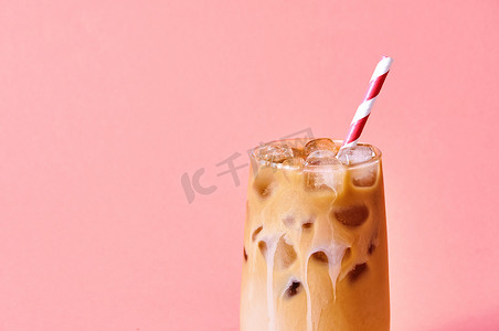拿牛奶摄影照片_特写镜头冰咖啡加牛奶在粉红色背景的高脚杯。