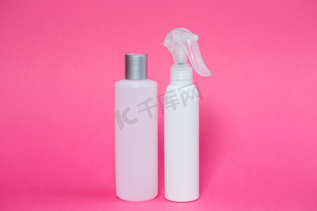 两个白色瓶子，里面有洗发水、身体凝胶、粉红色背景的皮肤喷雾
