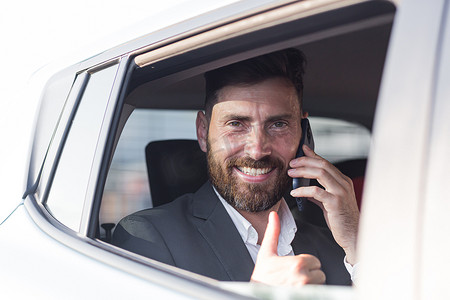 一名男子、一名汽车乘客打电话并望向开着的窗户外的特写肖像