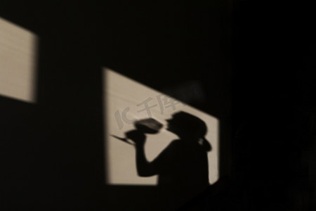 一位女侍酒师拿着一杯酒，墙上的影子。