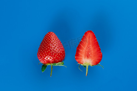 草莓切片特写和蓝色背景上的整块草莓。