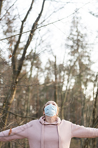 戴着医疗防护面罩的白人运动女性在森林中深呼吸放松时的肖像。
