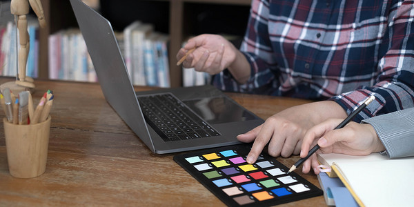 设计师图形创意与同事一起使用图形平板电脑和办公桌上的手写笔进行着色
