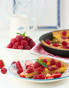 白桌上有红草莓和覆盆子的圆形乳蛋饼
