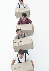 搬家工人摄影照片_年轻的搬家工人拿着箱子排成一排，被白色隔离