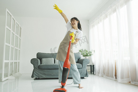 年轻女子在打扫房子时玩得开心。