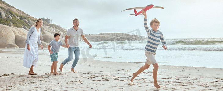 快乐的白人父母和孩子们一边玩玩具飞机，一边在海滩上享受轻松有趣的家庭暑假的美好时光。