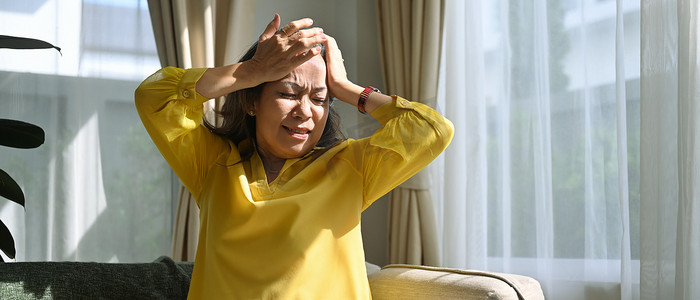 偏头痛摄影照片_不健康的成熟女性摸着她的头，患有头痛、偏头痛或头晕。