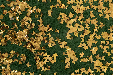 绿色背景上装饰性闪亮的金色星星五彩纸屑