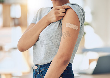 混血妇女在诊所或医院注射新冠疫苗后手臂上贴着创可贴的特写。