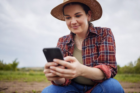 农民通过手机发短信或浏览社交媒体，获取在有机农场放松身心的在线可持续发展技巧。