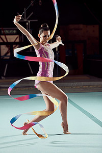 有创意的女性在健身房比赛中用丝带跳舞，舞者在地板上进行舞蹈表演，职业运动员在音乐会上表演。