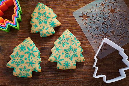 圣诞树形饼干，有雪花图案、模板、木制切板上的饼干切刀
