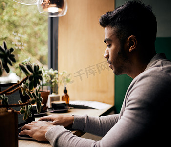 年轻的混血男子或学生在咖啡馆里用笔记本电脑浏览。