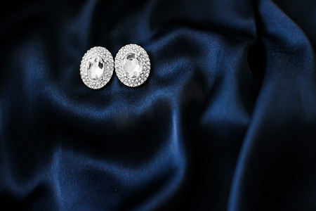 深蓝色丝绸背景的豪华钻石耳环，节日魅力珠宝礼物