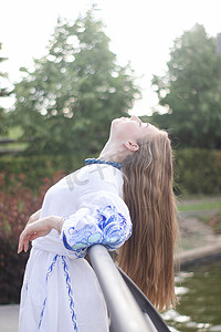 公园户外身穿蓝色民族传统刺绣衬衫的乌克兰年轻女子肖像