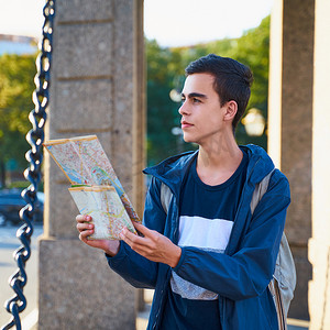 年轻人站在大城市的街道上，看着导游，一位在圣彼得堡寻找路线的游客