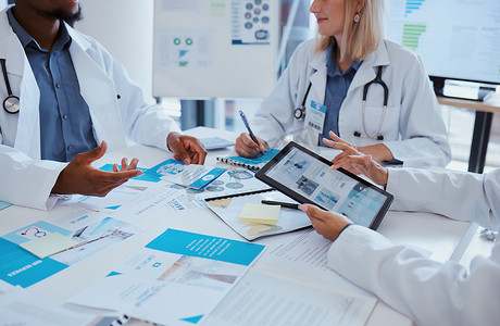 医疗保健医生和带有平板电脑数据的会议文件，用于在办公室进行业务讨论。
