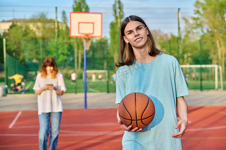 年轻人在户外游戏场打篮球的肖像，女孩失去了焦点。