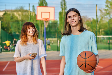 打篮球操场摄影照片_年轻人在户外游戏场打篮球的肖像，女孩失去了焦点。
