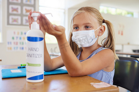 小学生消毒双手以防止感染新冠病毒，戴上口罩并遵循新的卫生安全程序。