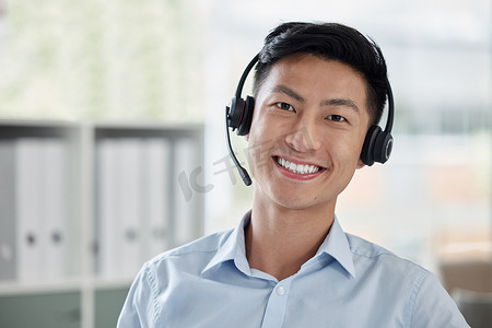 呼叫中心摄影照片_亚洲商人在呼叫中心工作，在明亮的办公室里微笑。