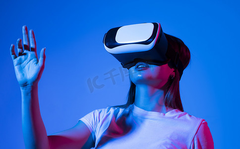 虚拟现实技术摄影照片_霓虹灯下的 VR 体验中触摸空气的女人。 