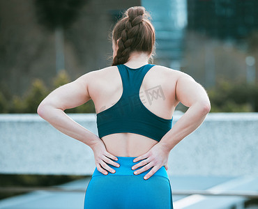 一名白人妇女在户外锻炼时从后面抱住酸痛的下背部。