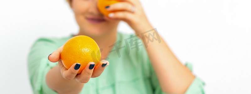 橙子并摄影照片_微笑的女营养师拿着整个橙子，在白色背景下提供并看着相机，健康的饮食概念。