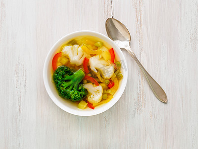 春花椰菜摄影照片_明春蔬菜饮食素食汤，配花椰菜、西兰花、胡椒、胡萝卜、青豆、欧芹。