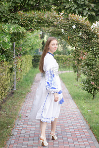 临夏民族大剧院摄影照片_公园户外身穿蓝色民族传统刺绣衬衫的乌克兰年轻女子肖像
