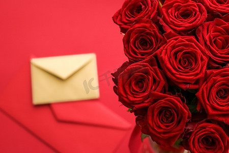信封书信摄影照片_情人节情书和鲜花递送服务、豪华红玫瑰花束和红色背景的卡片信封