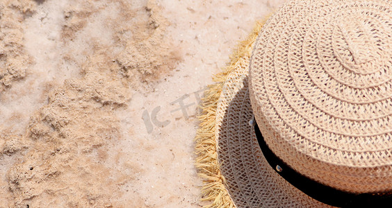 边顶摄影照片_一顶草帽躺在咸白色的沙滩上。