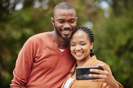 时尚的现代情侣在公园浪漫约会时用手机自拍，并在社交媒体应用程序上分享关系状态。