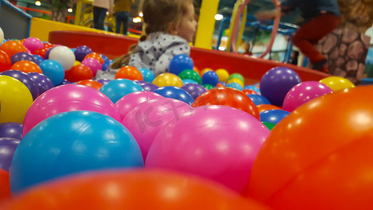 游乐园球摄影照片_快乐可爱的女孩在儿童游乐园和室内游乐中心的球坑里玩得开心。