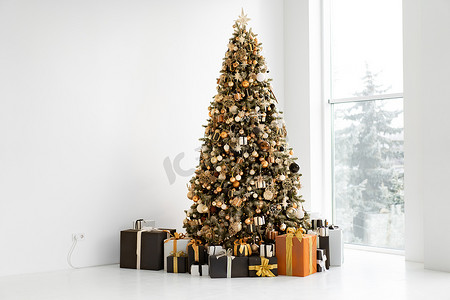 时尚礼盒摄影照片_白色内饰的圣诞树，配有时尚的黑色和橙色礼盒