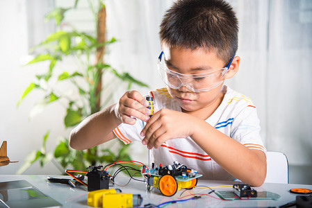 亚洲小男孩在家组装 Arduino 机器人汽车作业项目