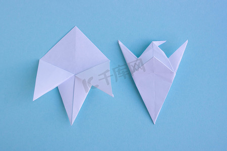 蓝色背景上手工制作的白色时尚几何多边形纸折纸鱼。步骤 3。