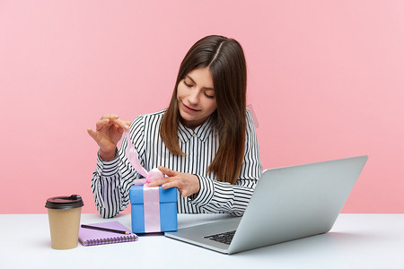 购物节购物节摄影照片_情绪化的年轻女性坐在粉红色背景的办公室里工作。