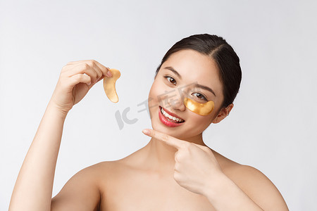 亚洲美女少女用眼下的金色眼罩贴片护理皮肤