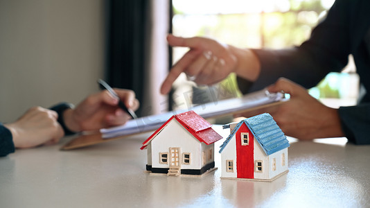 白桌上的两个小房子模型，客户与后台代理签订合同。