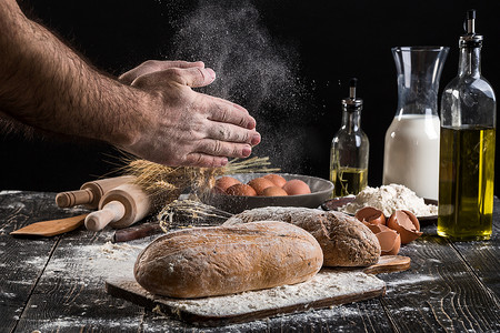撒面粉摄影照片_厨师在新鲜面包上撒上面粉。